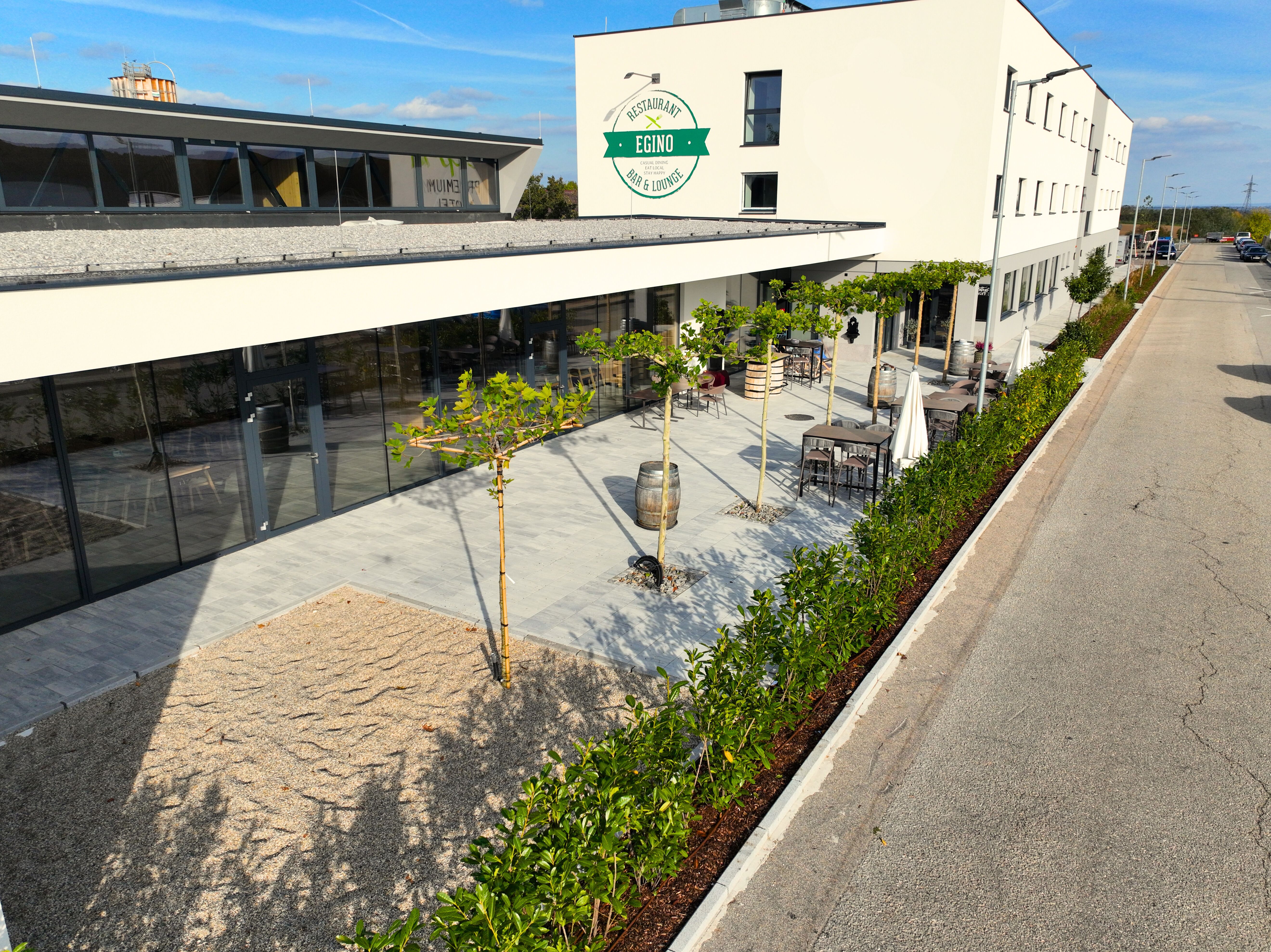 Pohled zvenčí na moderní budovu s terasou a rostlinami.