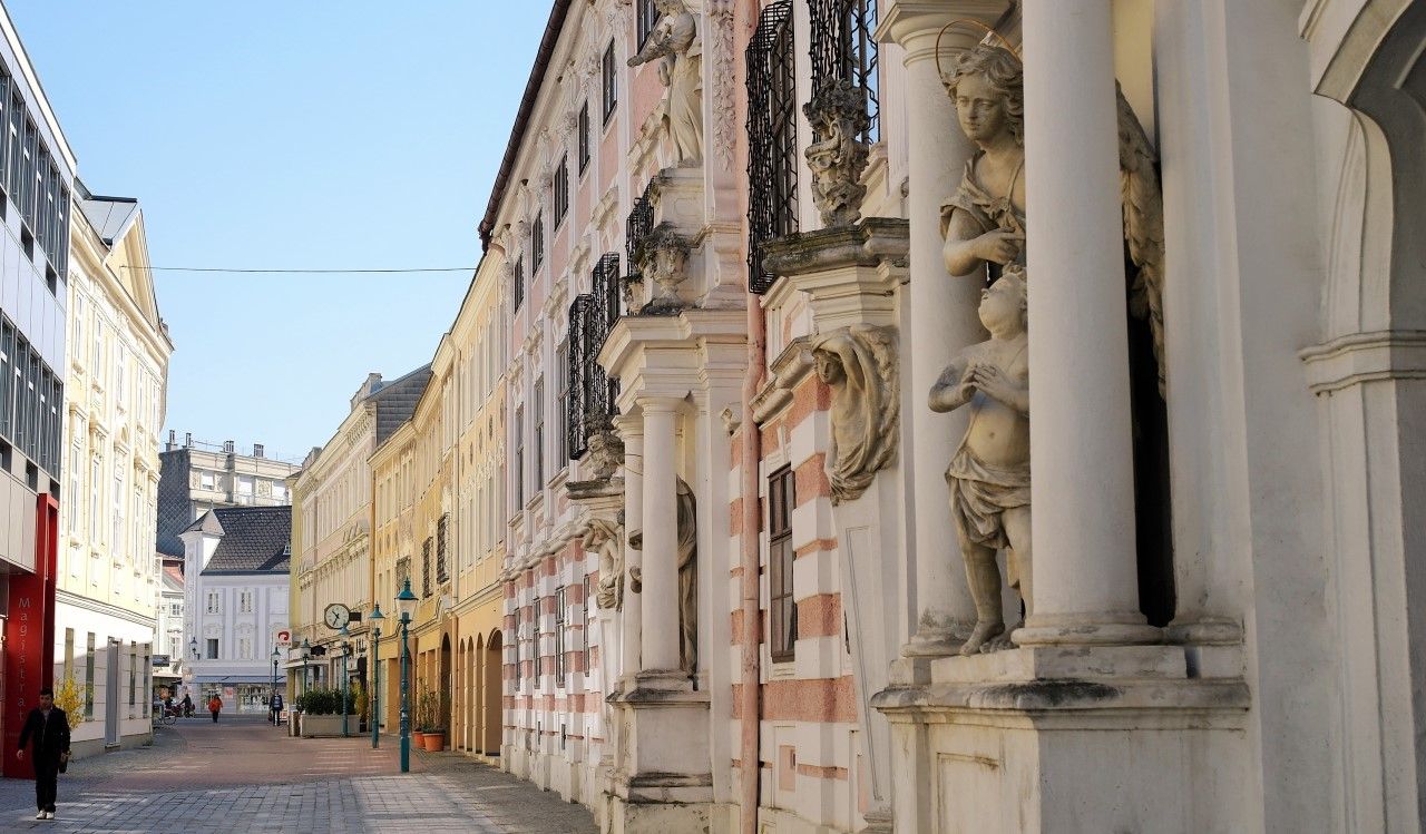 Ulice s historickými budovami a sochami ve městě.