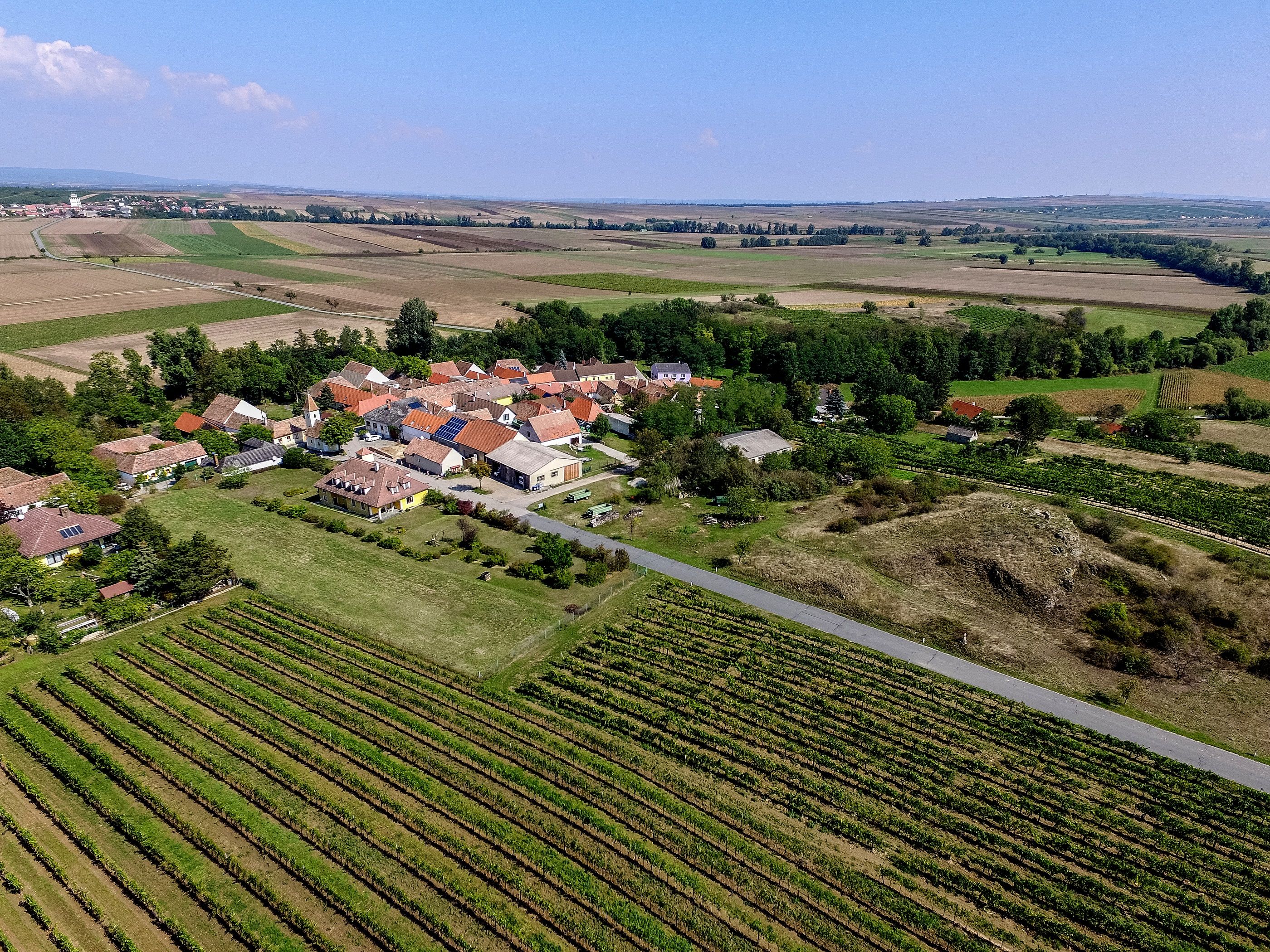 Letecký pohled na malou vesnici obklopenou poli a vinicemi.