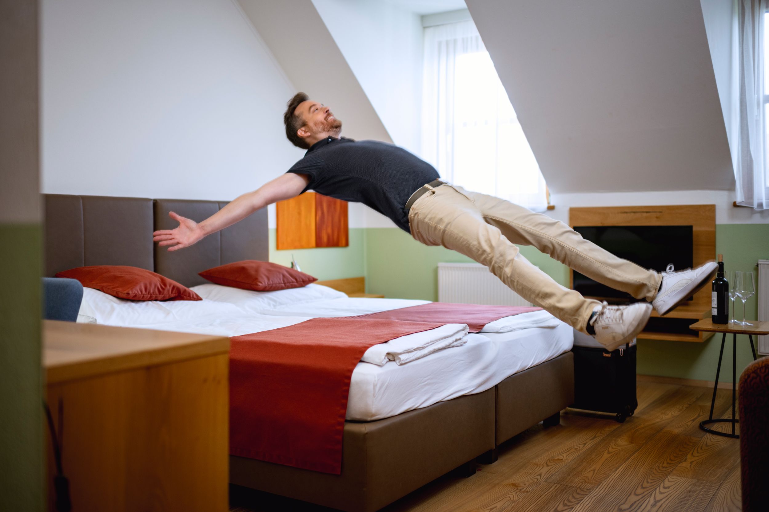 Dvoulůžkový pokoj vinařství & pokoj pro hosty Edelmann, muž skáče na posteli