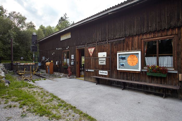 Dřevěná budova s nápisy a květinami, součást výstavy.
