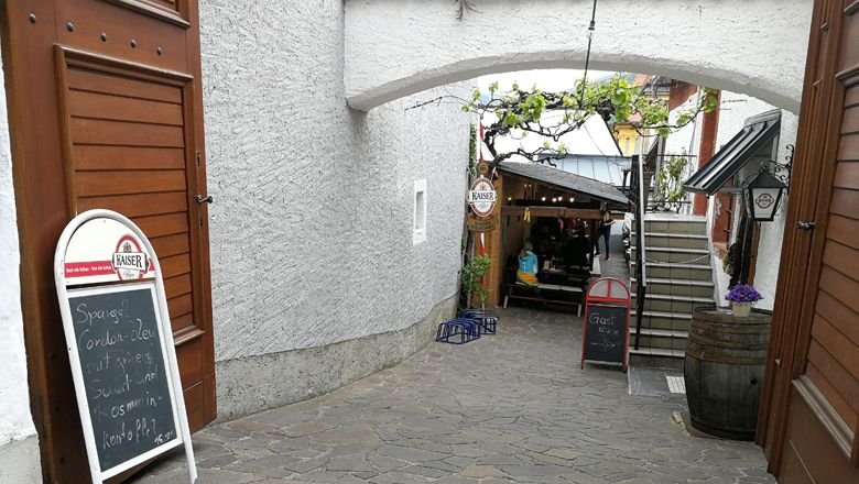 Vstup do útulného dvora se stoly a rostlinami.