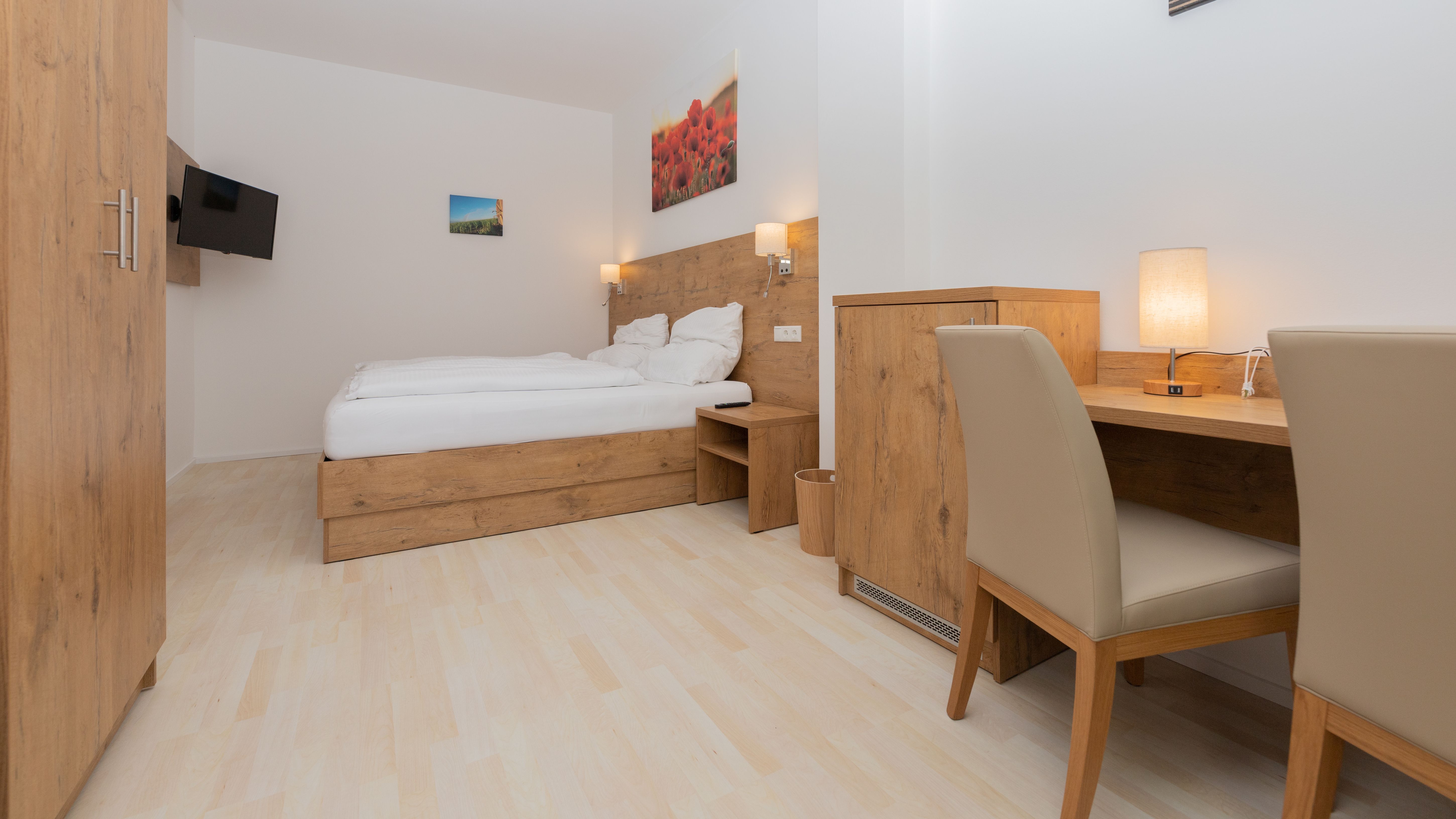 Moderní ložnice s dřevěným nábytkem, manželskou postelí, psacím stolem a TV s plochou obrazovkou.