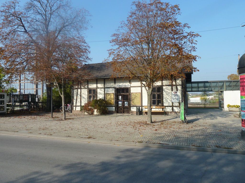 Stará budova železničního muzea Deutsch-Wagram se stromy v popředí.
