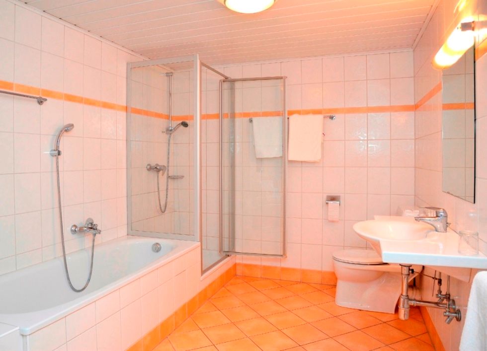 Moderní koupelna s vanou, sprchovým koutem, umyvadlem a toaletou.