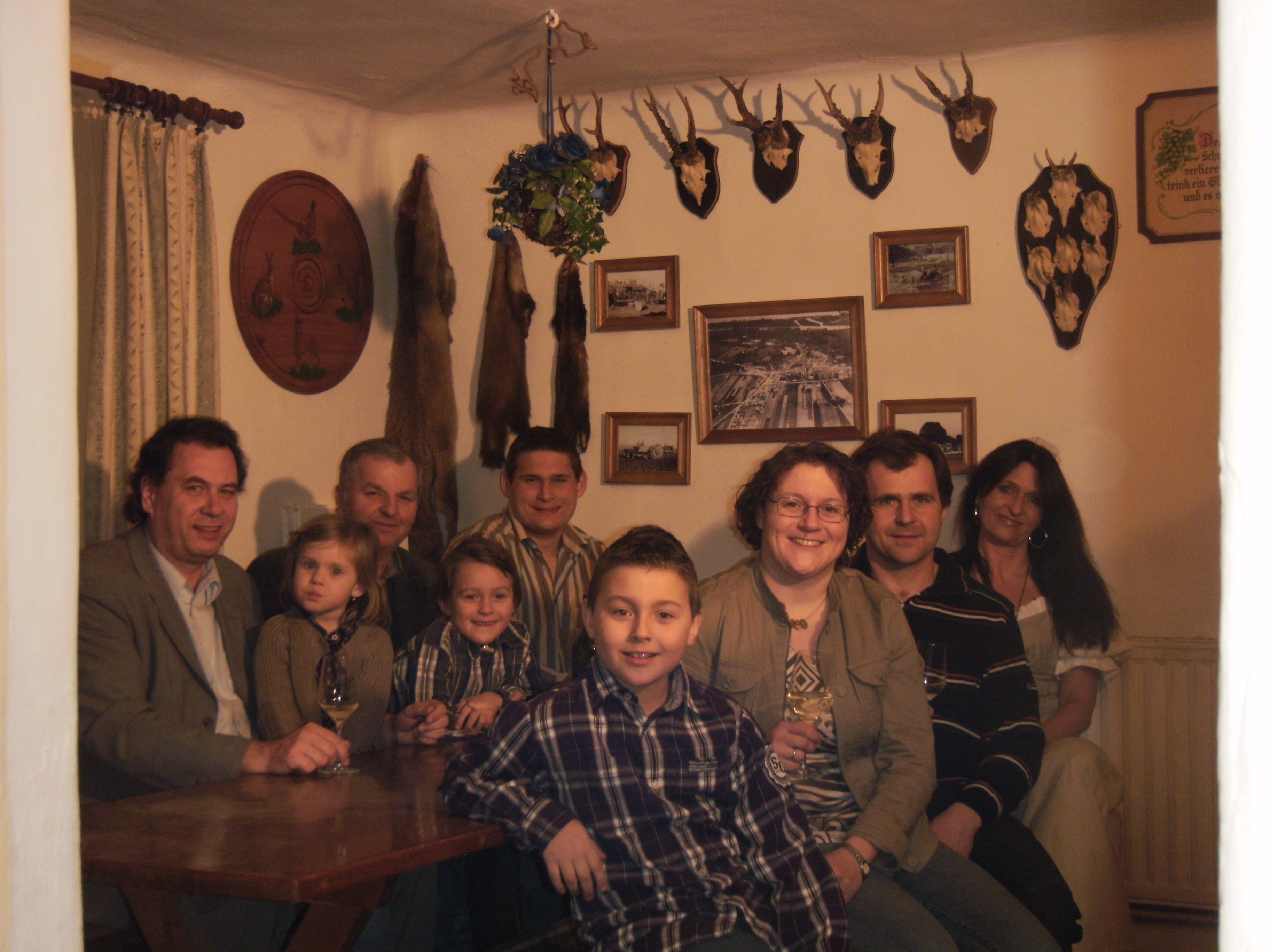 Skupina lidí sedí v místnosti s loveckými trofejemi na stěnách.