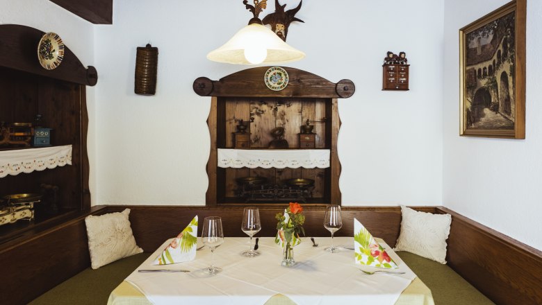 Útulné posezení v restauraci s dřevěným nábytkem, dekorativními detaily a prostíráním.