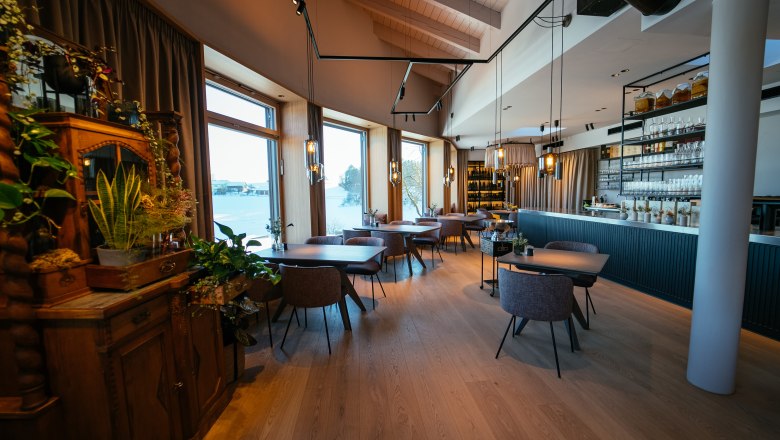 Elegantní restaurace s dřevěnými podlahami, velkými okny a stylovým nábytkem.