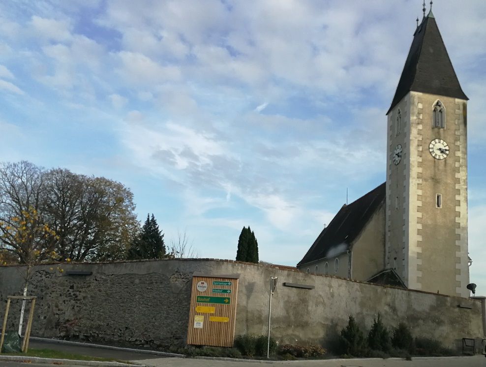 Kostel s věží a hodinami v Hafnerbachu, obehnaný zdí.