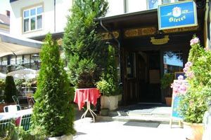 Vchod do restaurace s rostlinami a nápisy.