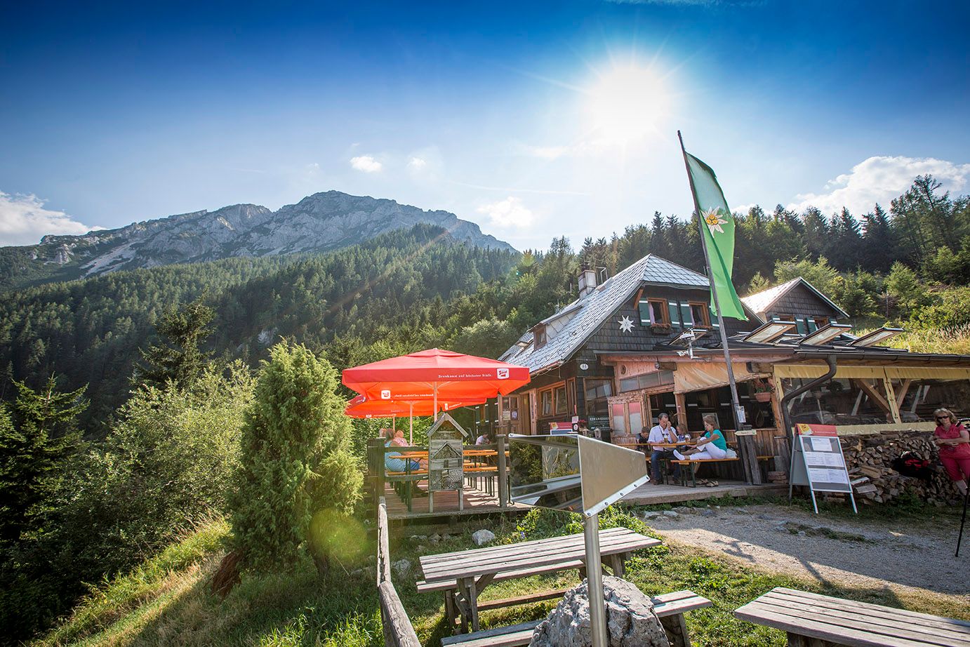 Chata Edelweiss na Schneebergu se slunečníky a horskou kulisou.