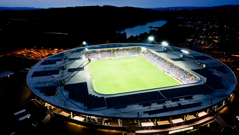 Letecký pohled na osvětlený fotbalový stadion v noci.