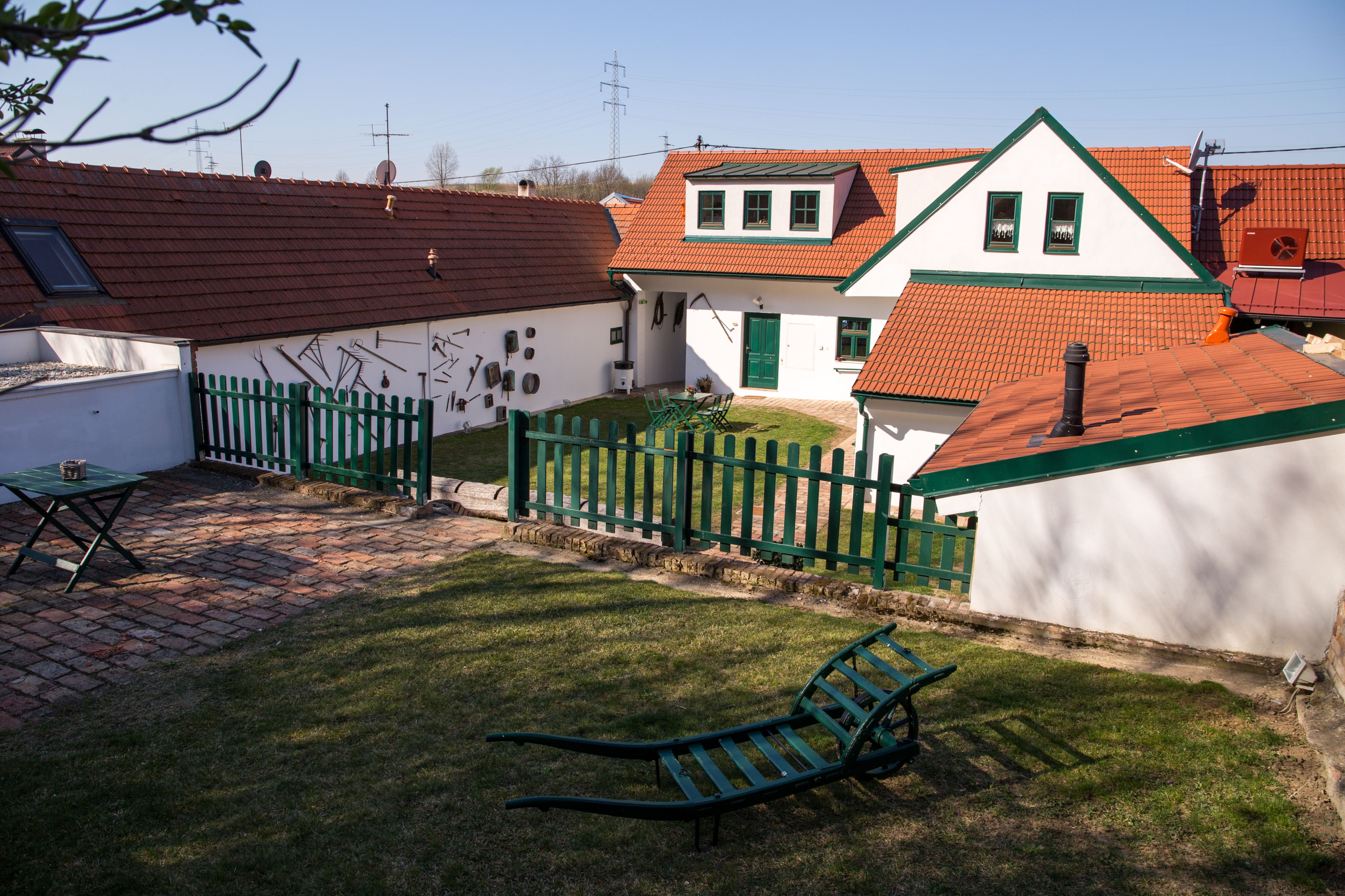 Tradiční vinice s červenými taškovými střechami, zelenými ploty a zahradním nábytkem na louce.