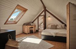 Rustikální kamenný dům s dřevěnými dveřmi, lavičkou a květinami v popředí.