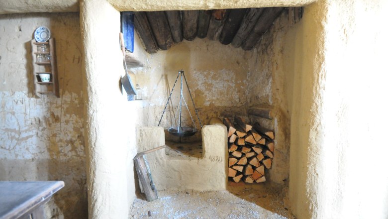 Pohled do interi&eacute;ru rustik&aacute;ln&iacute; m&iacute;stnosti s krbem a hromadou dřeva.