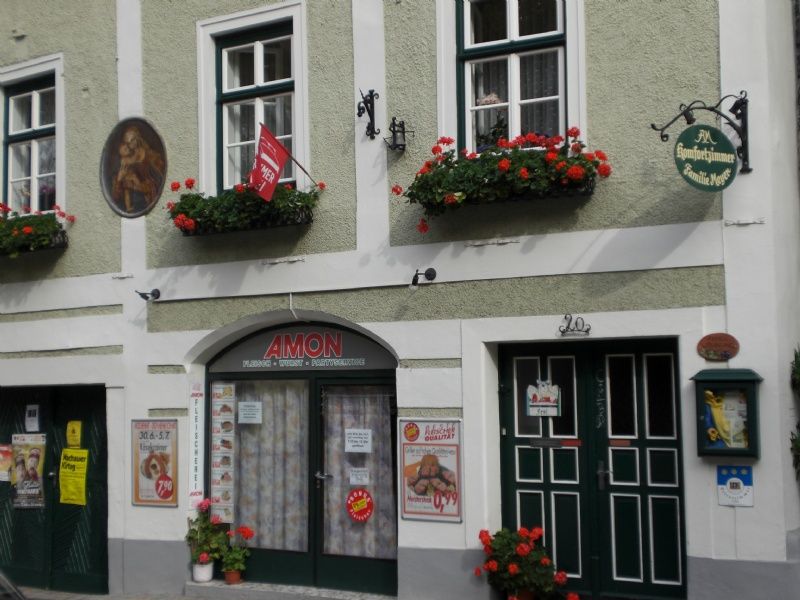 Vnější pohled na budovu s květinami a nápisy.