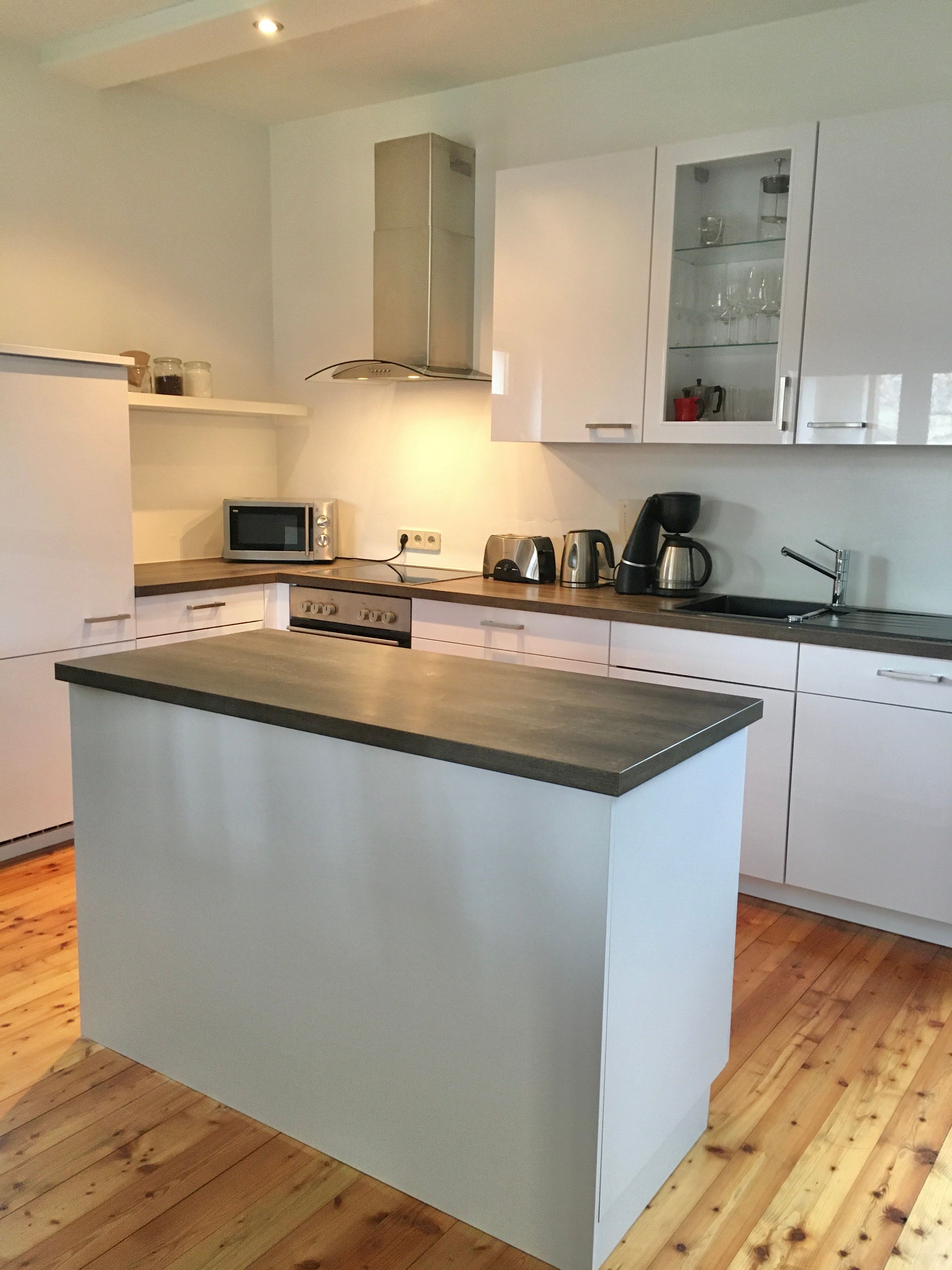 Moderní kuchyně s ostrůvkem, bílými skříňkami a spotřebiči.