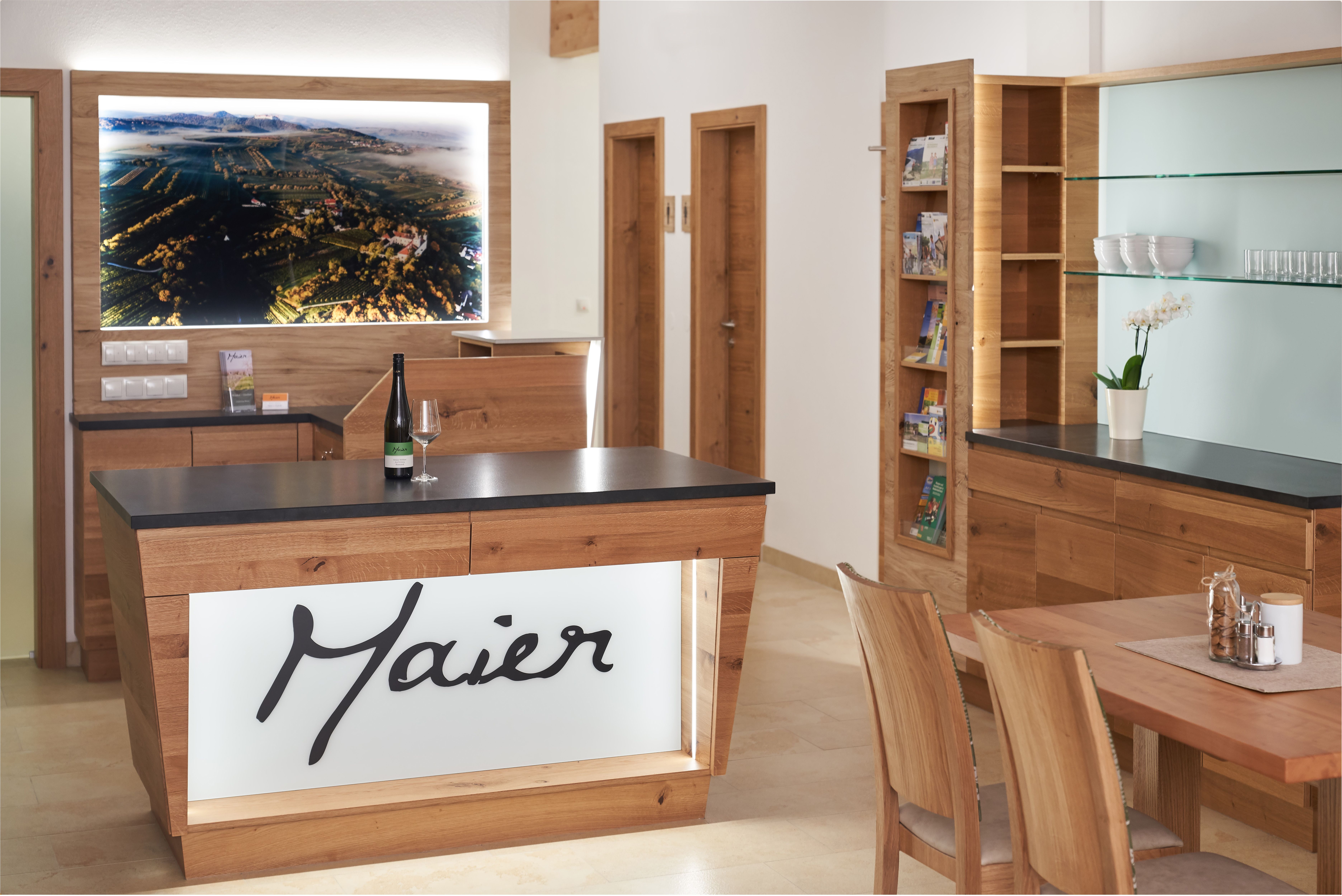 Pohled do interiéru moderní recepce s dřevěným nábytkem a velkou krajinomalbou na stěně.