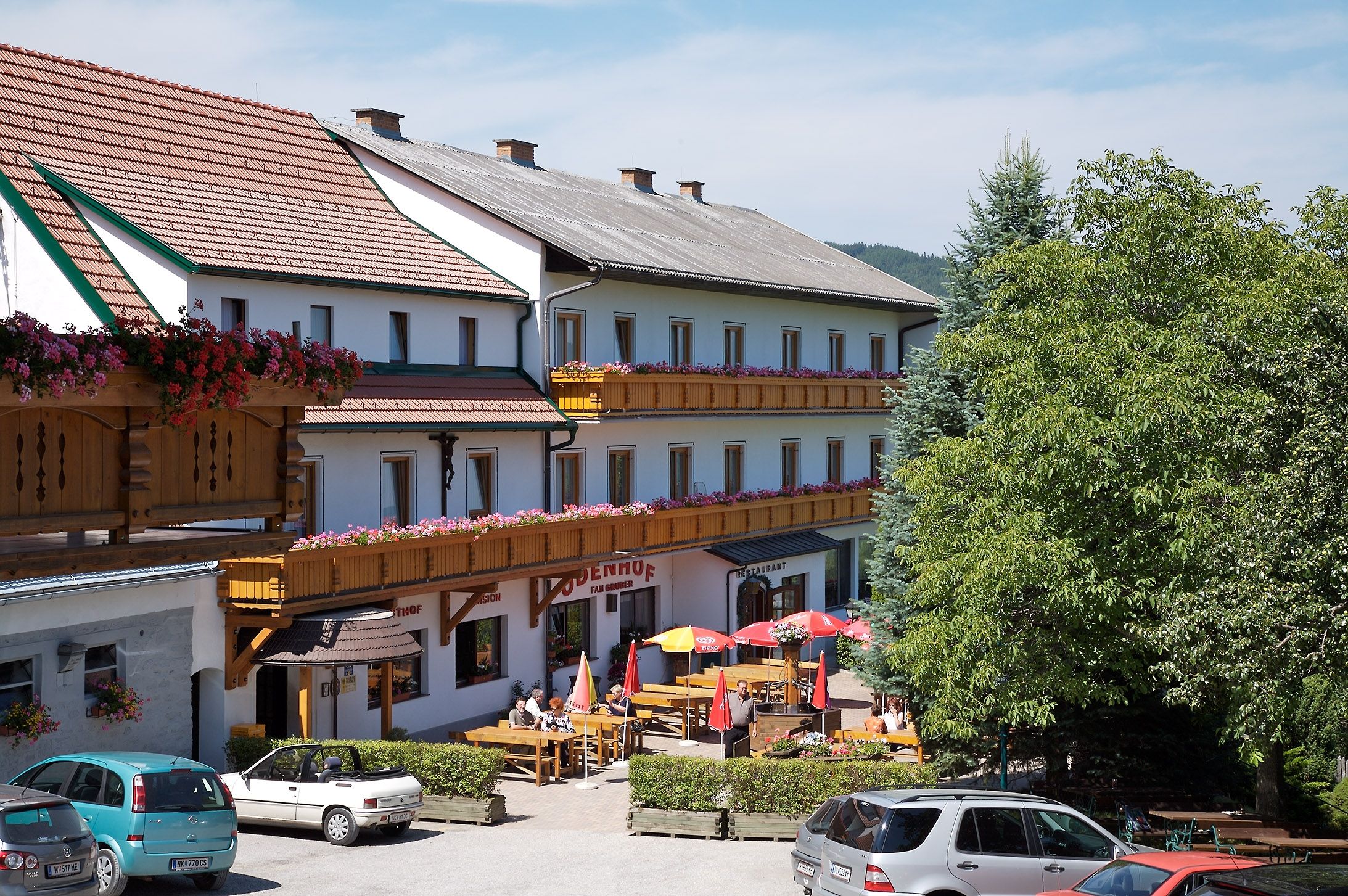 Gasthof-Pension Ödenhof s terasou a zaparkovanými auty.