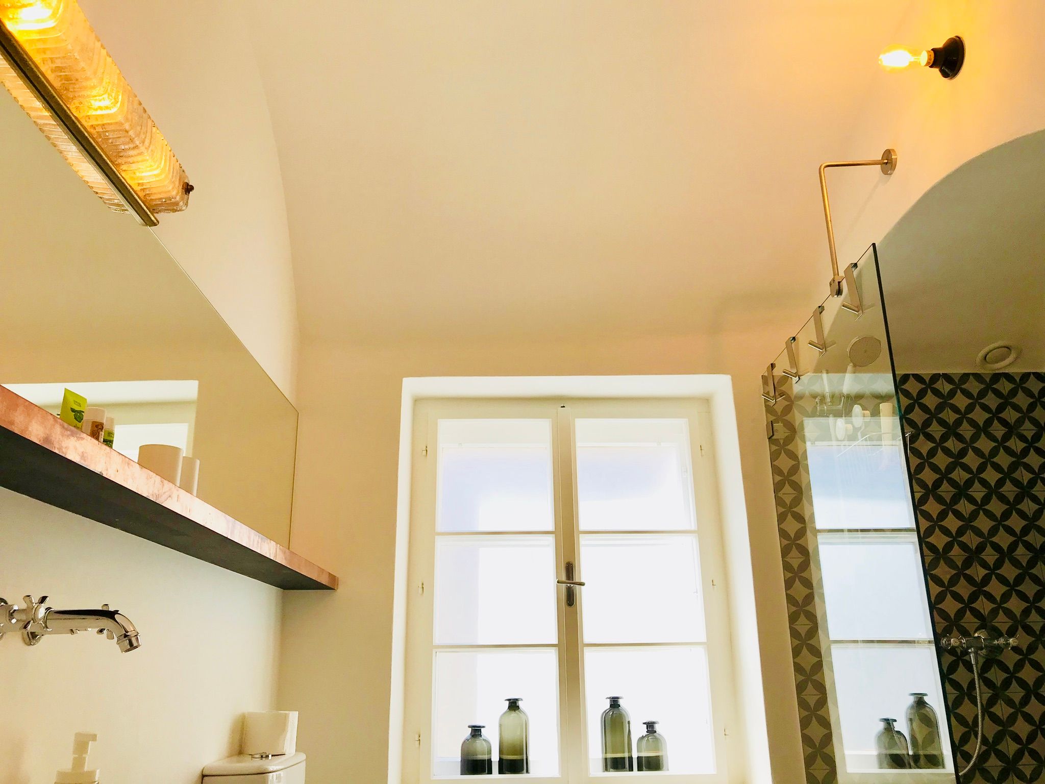 Moderní koupelna se skleněným sprchovým koutem a dekorativními obklady.