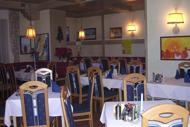 Útulná restaurace s dřevěným nábytkem, prostřenými stoly a nástěnnými dekoracemi.