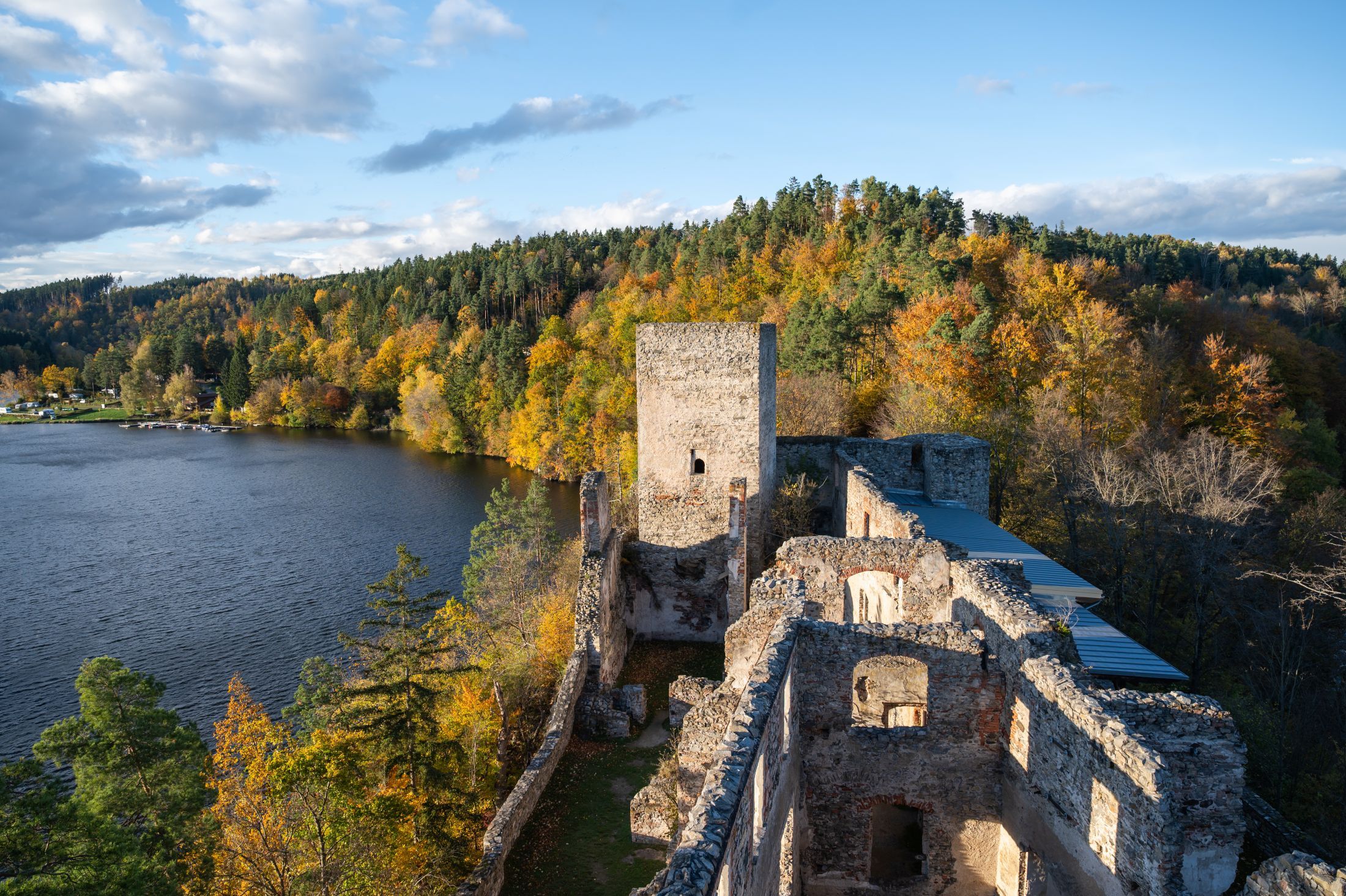 Zřícenina Dobra s výhledem na jezero a podzimní les.