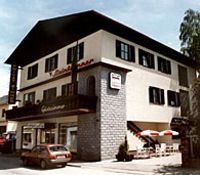 Dvoupodlažní budova s balkonem a terasou, označená "Steinbrunner".