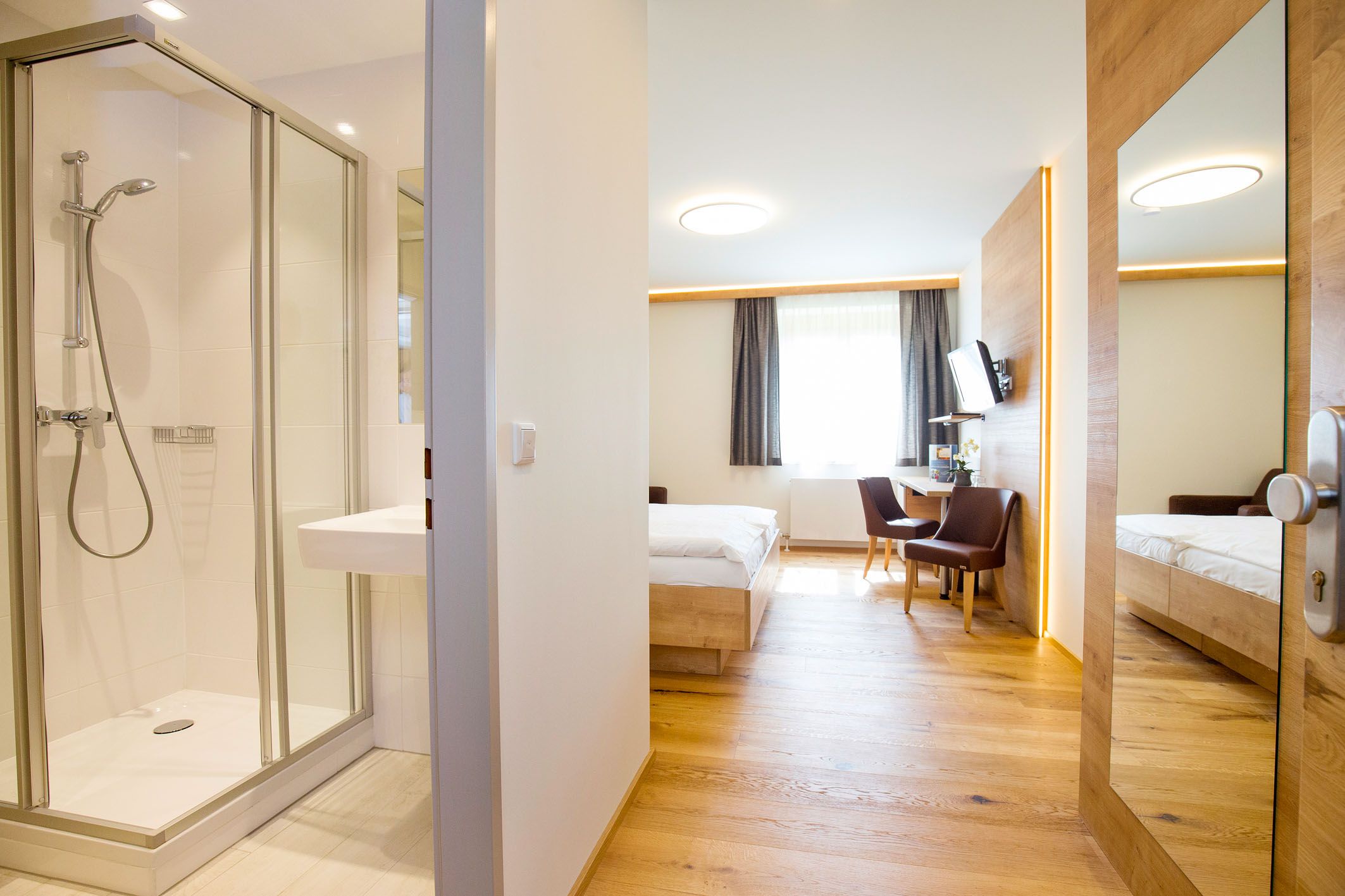 Moderní hotelový pokoj s koupelnou, postelí, stolem a židlemi.