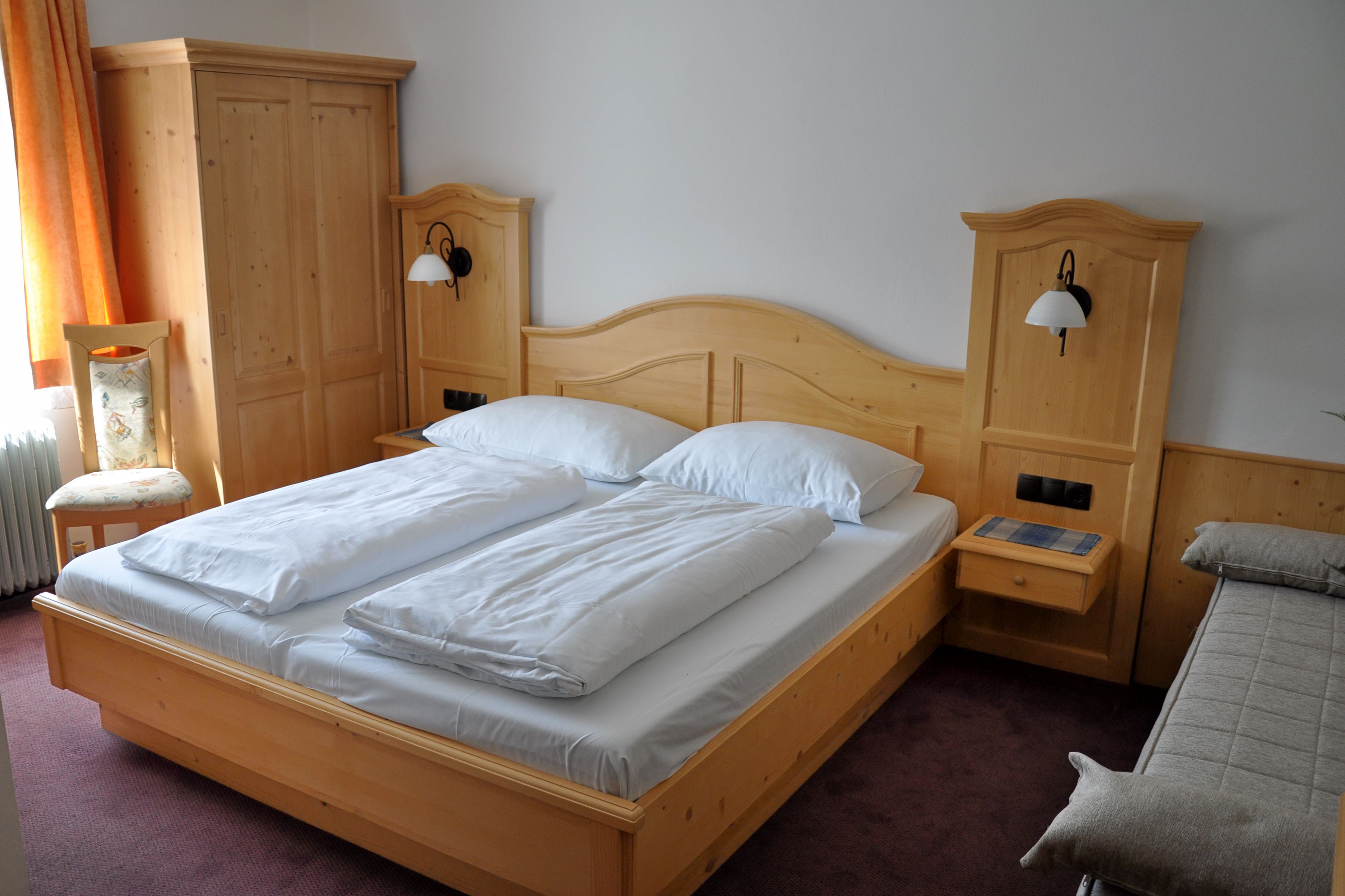 Pokoj Comfort s manželskou postelí a nábytkem z masivního dřeva.