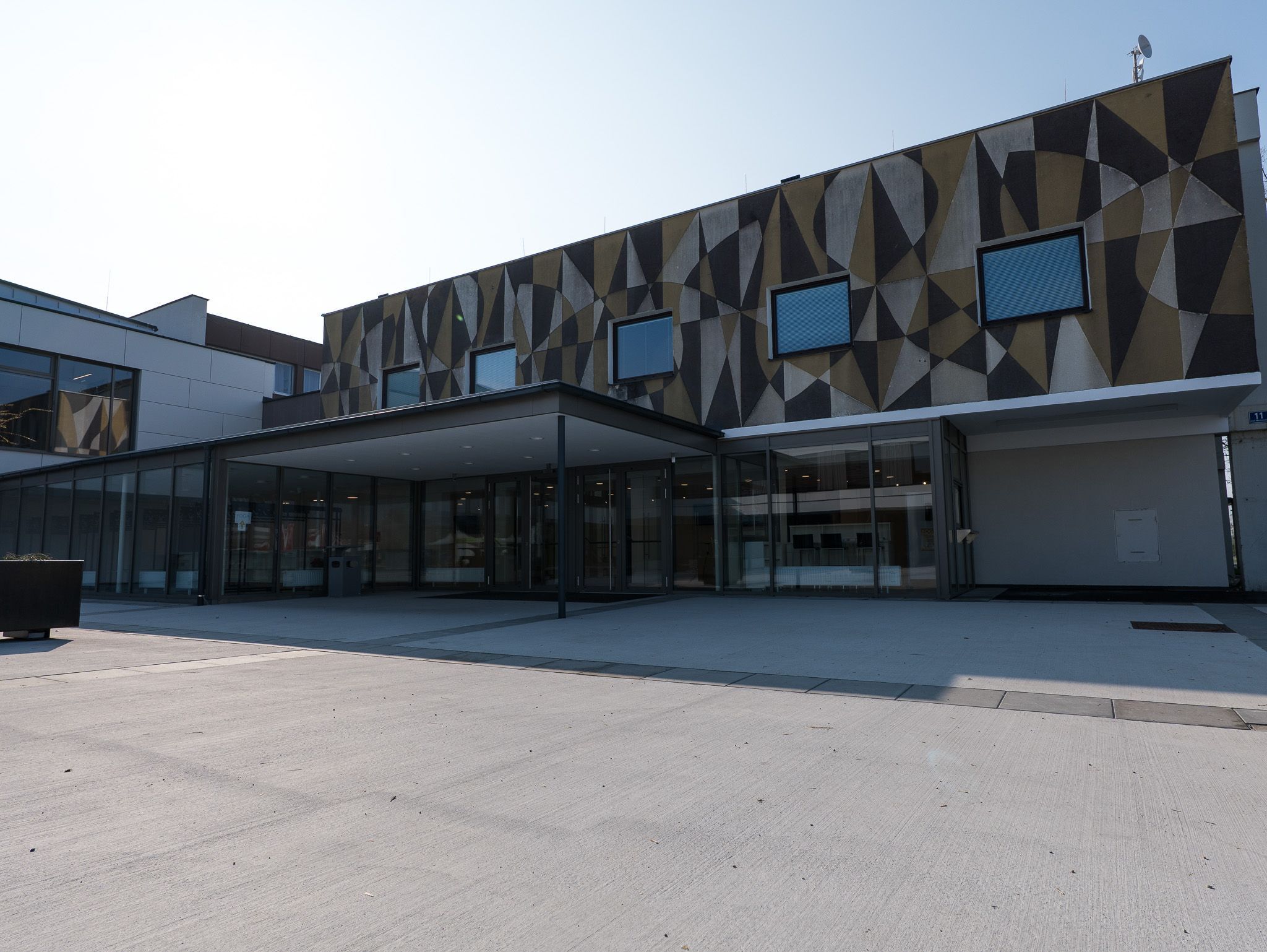 Vnější pohled na moderní budovu s geometrickými vzory na fasádě.