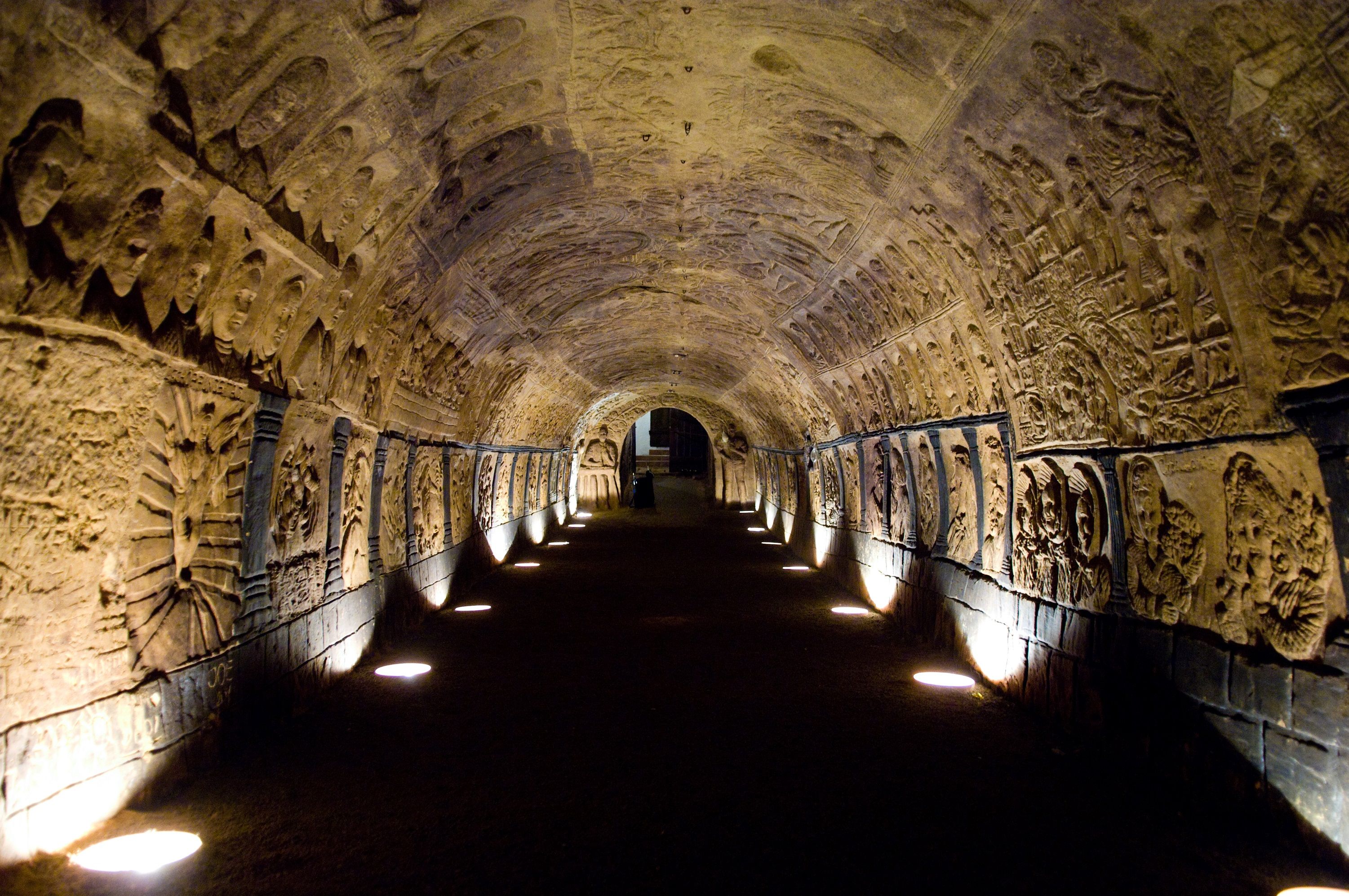 Osvětlený tunel zdobený reliéfy v historickém sklepení.
