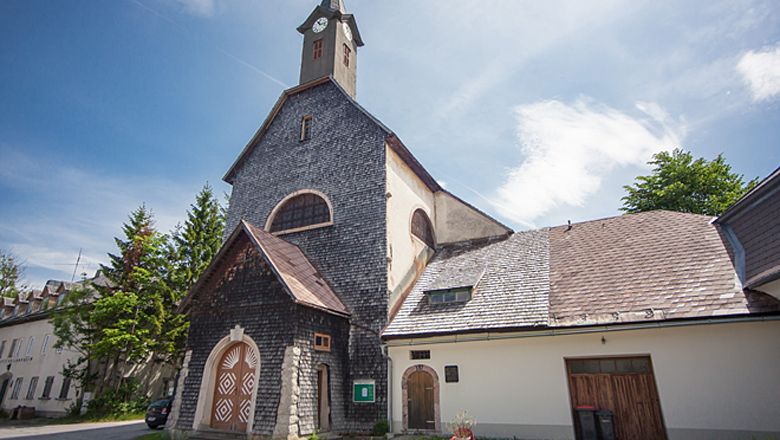 Josefsberský farní kostel s kamennou fasádou a věží pod modrou oblohou.