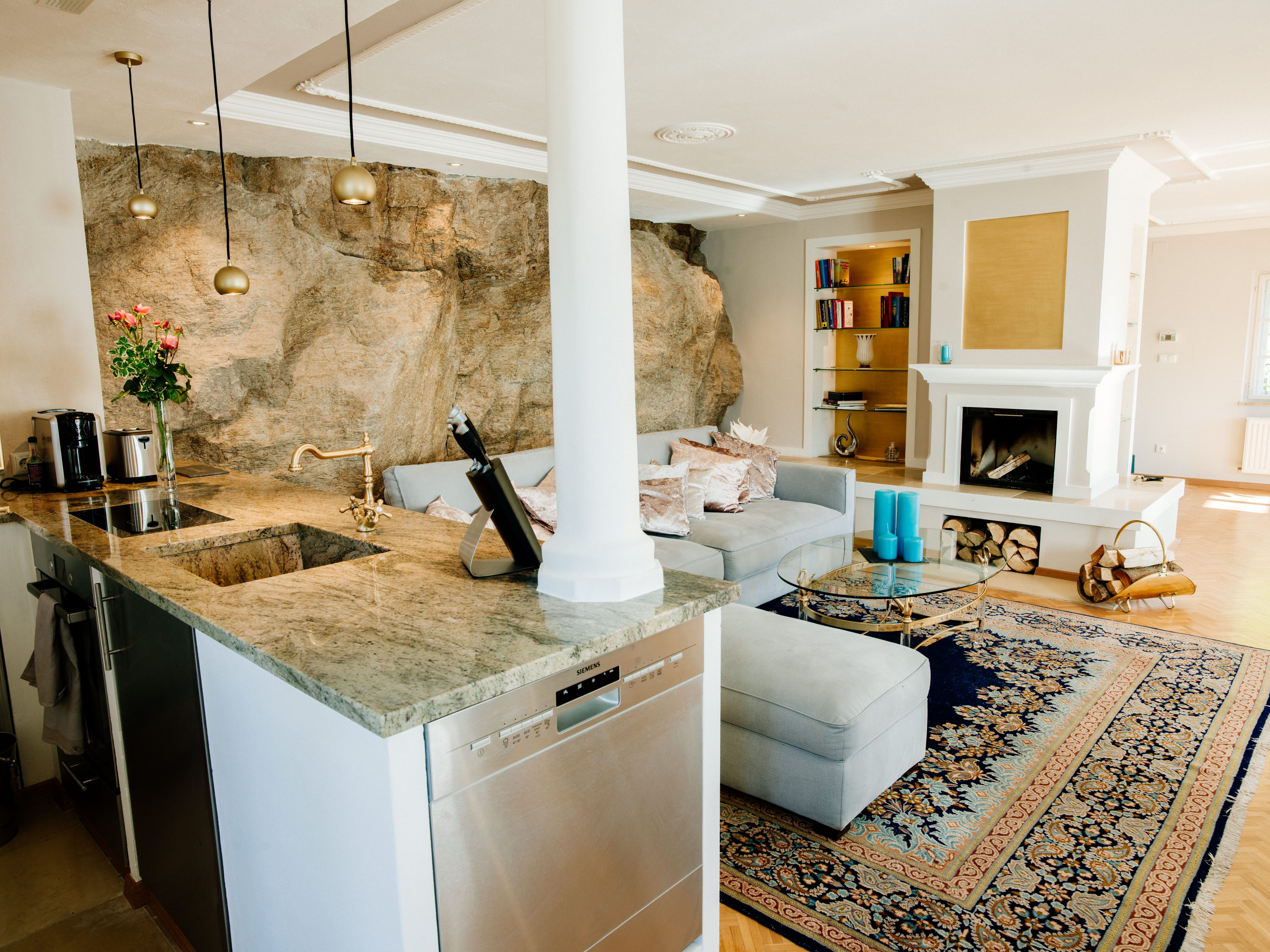 Elegantní obývací pokoj s krbem, kobercem a otevřenou kuchyní.