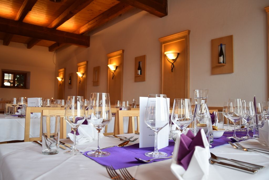 Elegantní restaurace s prostřenými stoly, sklenicemi na víno a fialovými ubrousky.