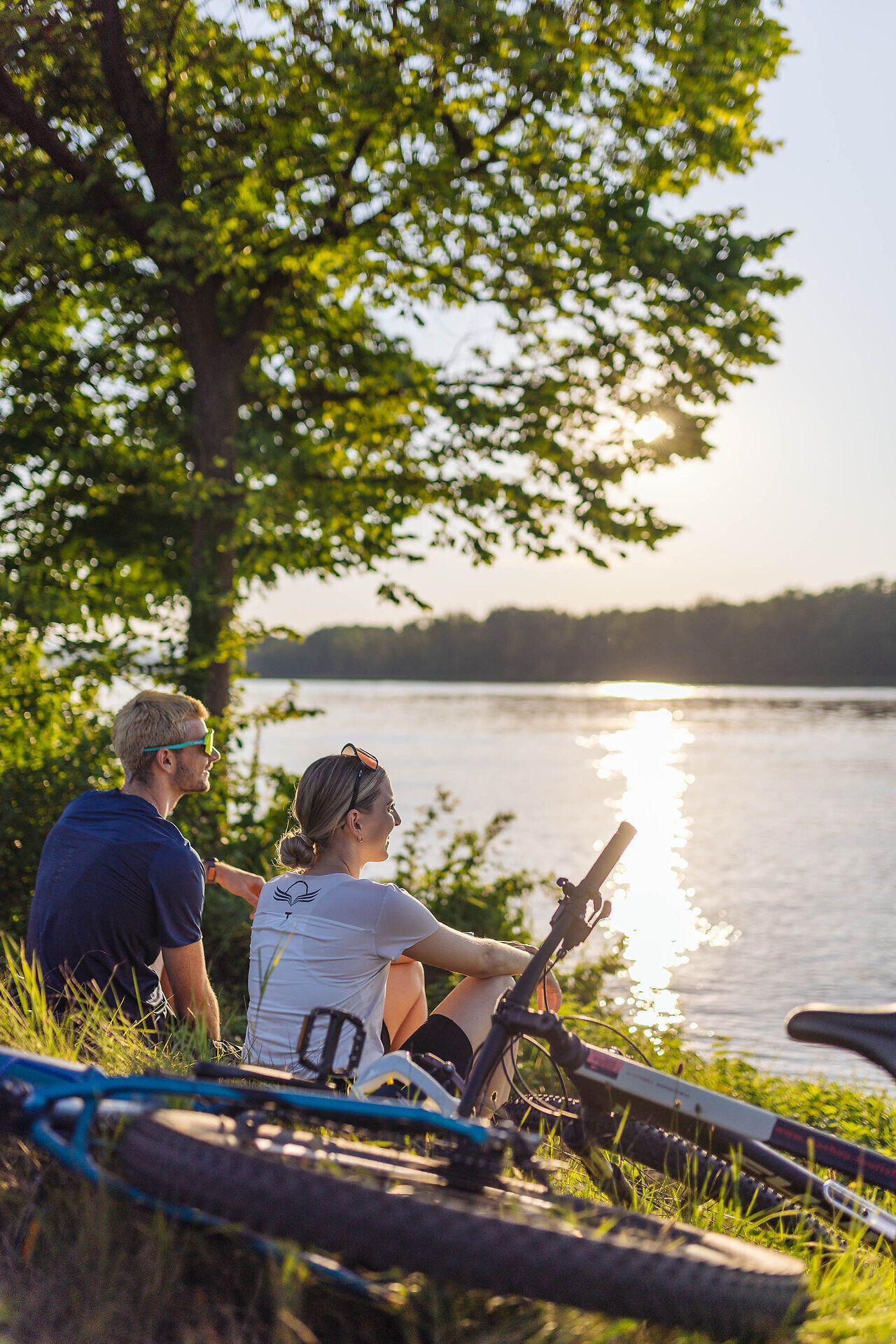 Ein Pärchen sitzt am Donauufer und hat die Räder daneben in die Wiese gelegt.