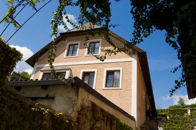 Pohled zvenčí na tradiční dům porostlý břečťanem, v pozadí modrá obloha.