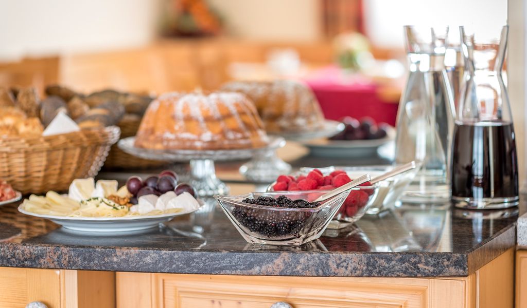 Snídaně formou bufetu s koláči, lesním ovocem, sýrovým talířem a nápoji na stole.