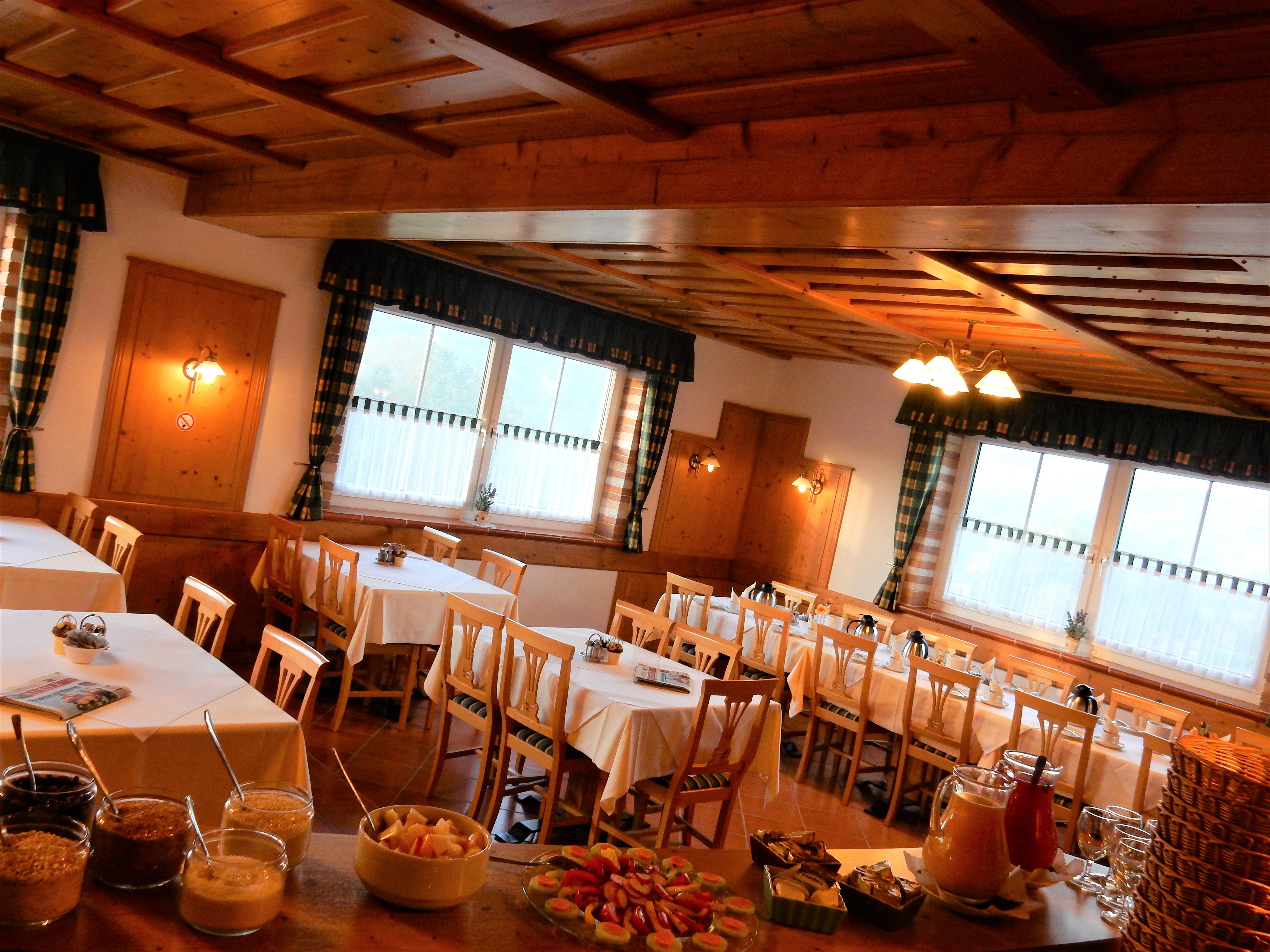 Útulná snídaňová místnost s dřevěným nábytkem a prostřenými stoly.