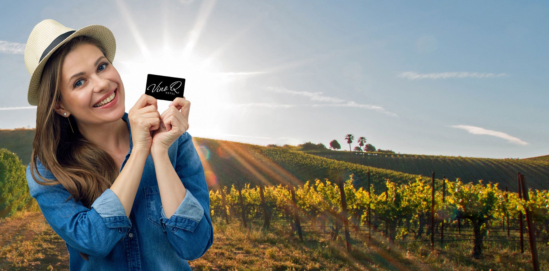 Žena s kloboukem držící Mapu před prosluněnou vinicí.