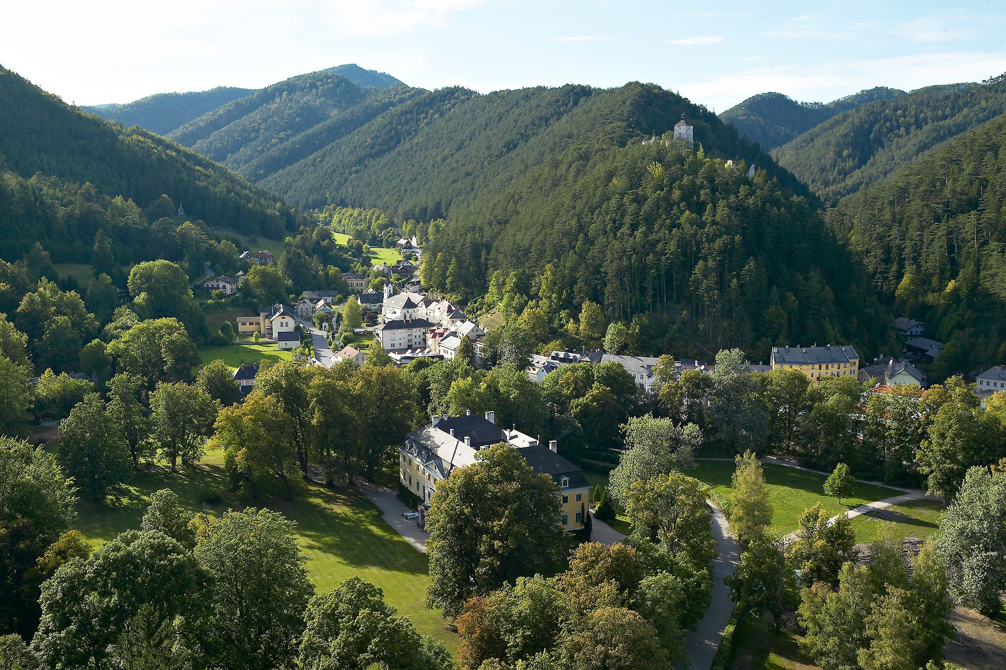 Letecký pohled na Gutenstein se zelenými kopci a hradem na kopci.