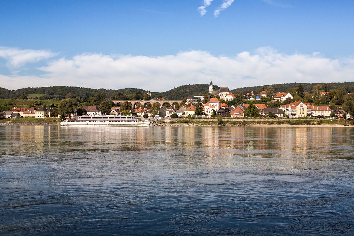 Panorama obce Emmersdorf an der Donau s lodí na řece.