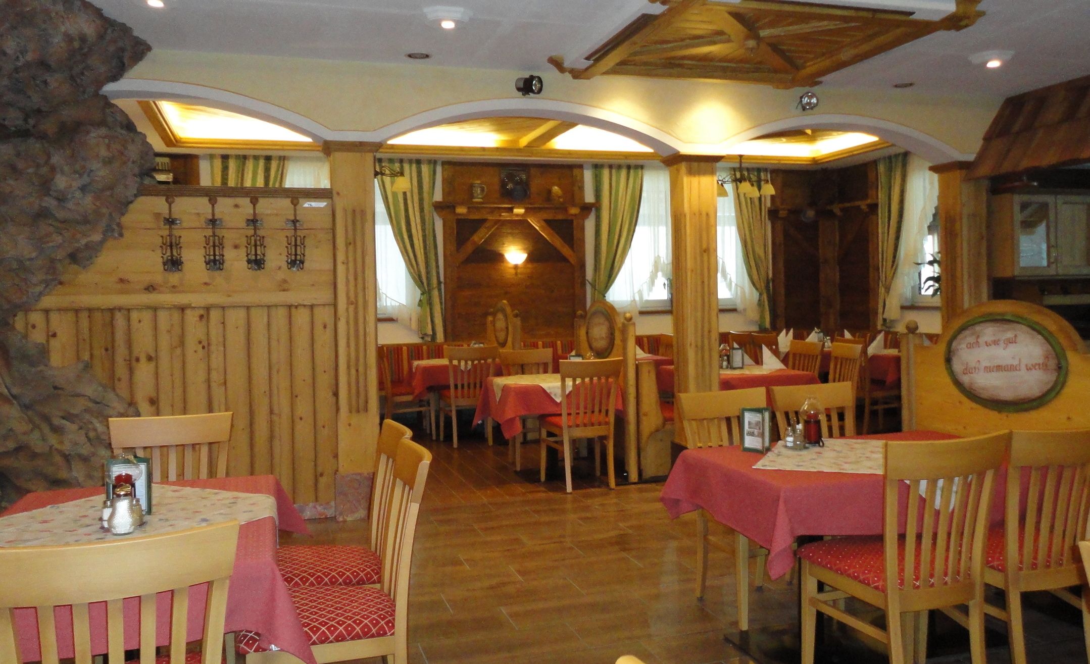 Útulná restaurace s dřevěným nábytkem a červenými ubrusy.