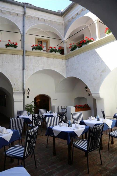 Vnitřní nádvoří hostince s prostřenými stoly a květinami.