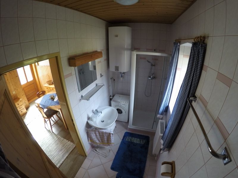 Koupelna se sprchou, umyvadlem, pračkou a modrými závěsy.