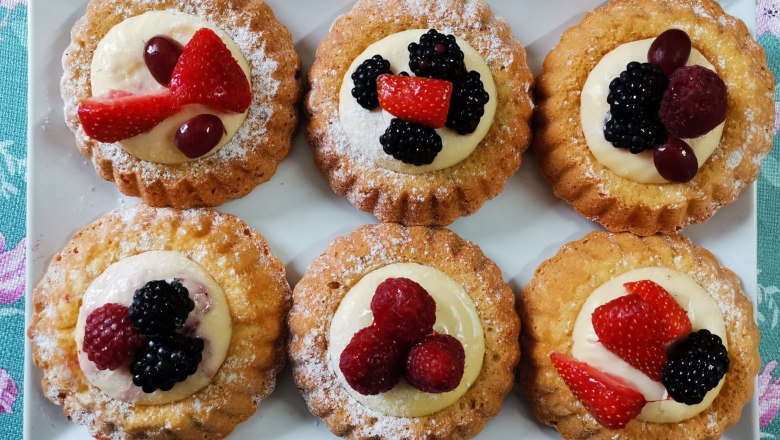 &Scaron;est mal&yacute;ch ovocn&yacute;ch kol&aacute;čů na b&iacute;l&eacute;m tal&iacute;ři, zdoben&yacute;ch bobulemi a smetanou.