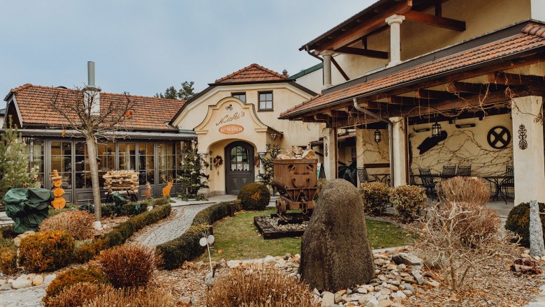 Pohled zvenčí na tradiční hospodu se zahrádkou a výzdobou.