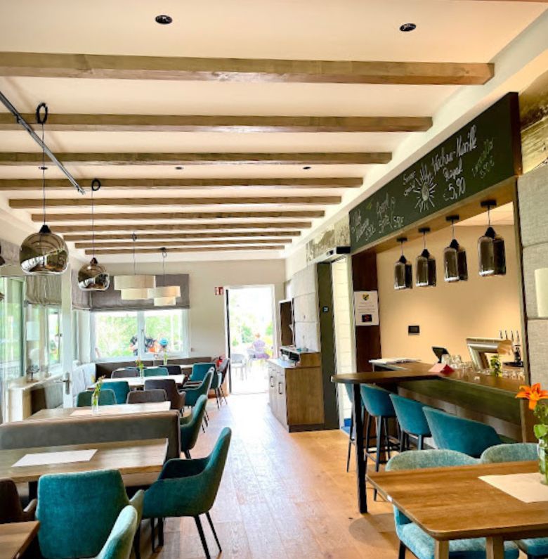 Restaurace uvnitř se stoly a zelenými křesly