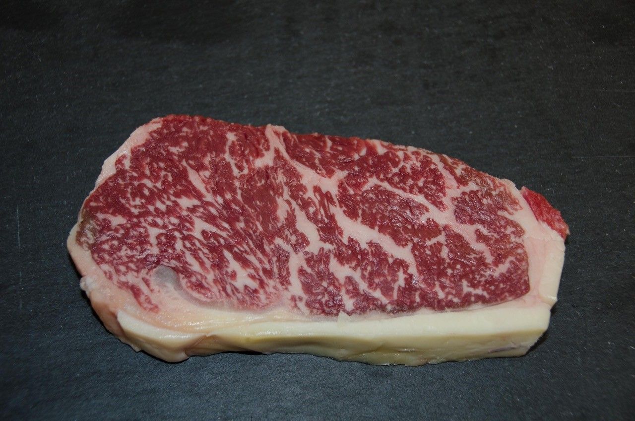 Kus hovězího masa Wagyu s výrazným mramorováním na černém pozadí.