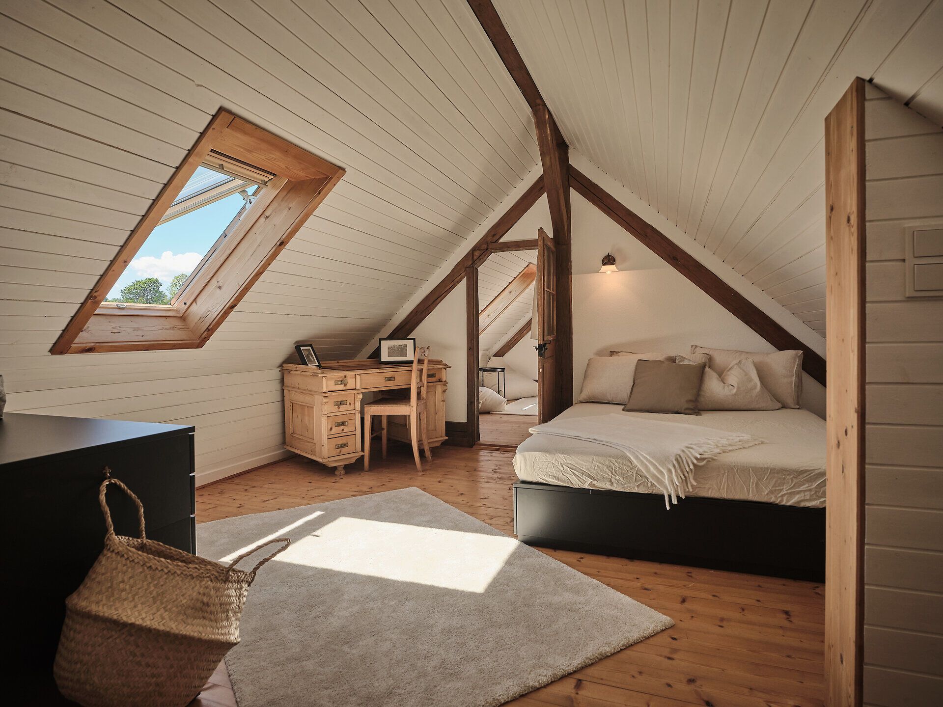 Rustikální kamenný dům s dřevěnými dveřmi, lavičkou a květinami v popředí.