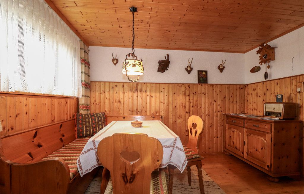 Útulný sklepní salonek s dřevěným nábytkem, rohovou lavicí, stolem, rádiem a loveckými trofejemi na stěně.